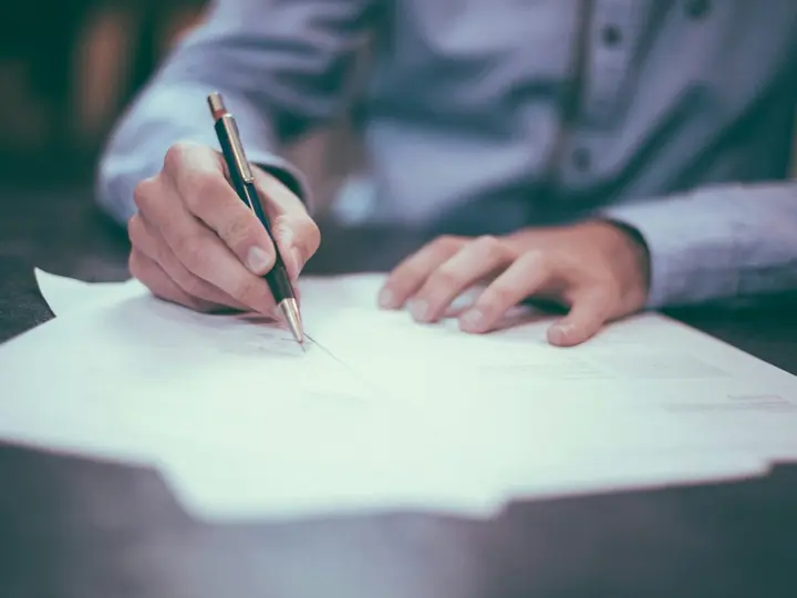 Hand unterschreibt ein Dokument mit einem Stift